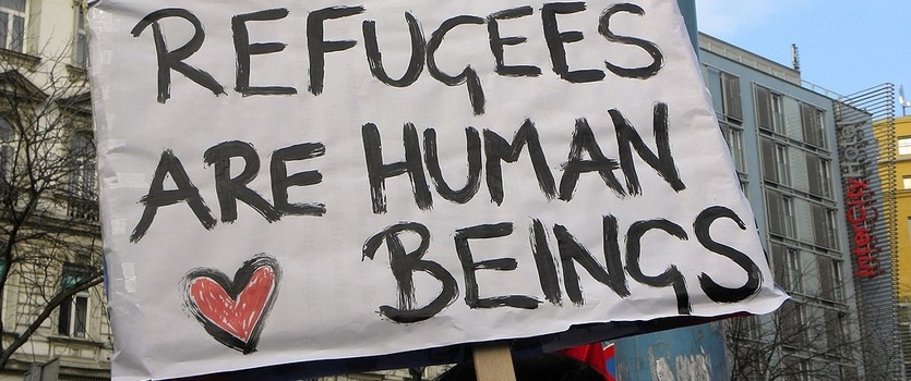 protest sign saying 'refugees are human beings' with a cartoon heart