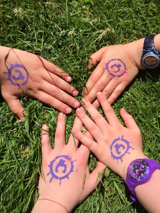 The hands of four children painted with a symbol.