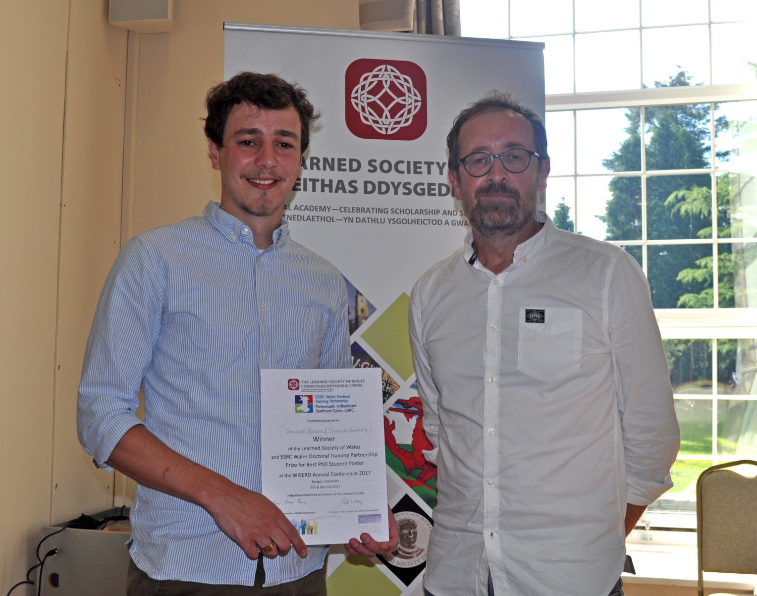 Samuel Brown holding his certificate next to Prof Chris Taylor