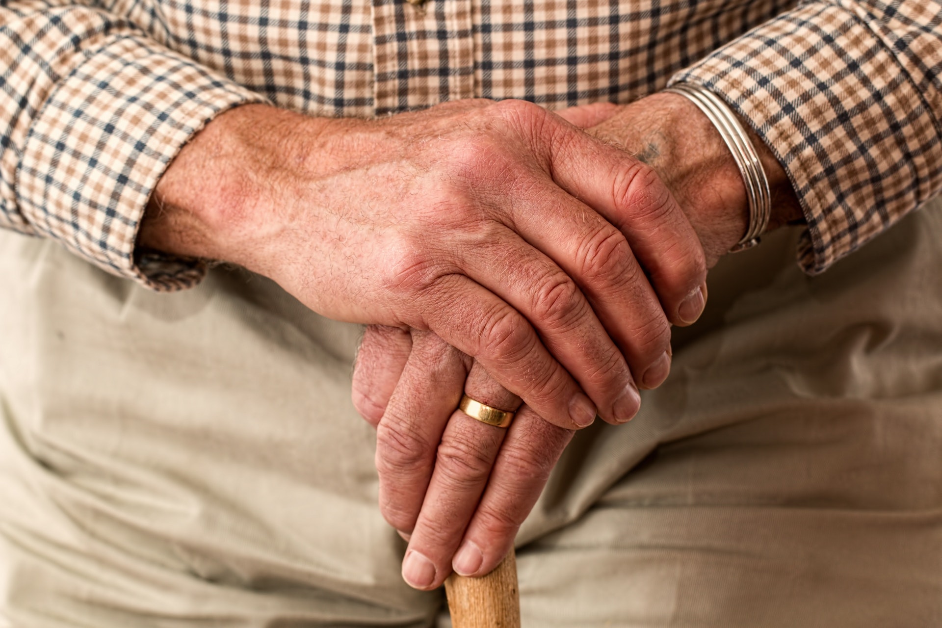 Old man hands resting on a walking stick