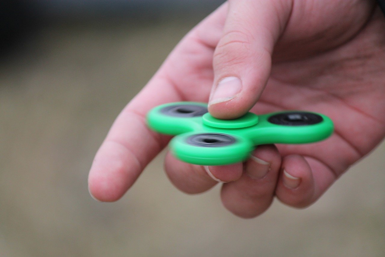 Close up picture of a hand holding a green fidget spinner
