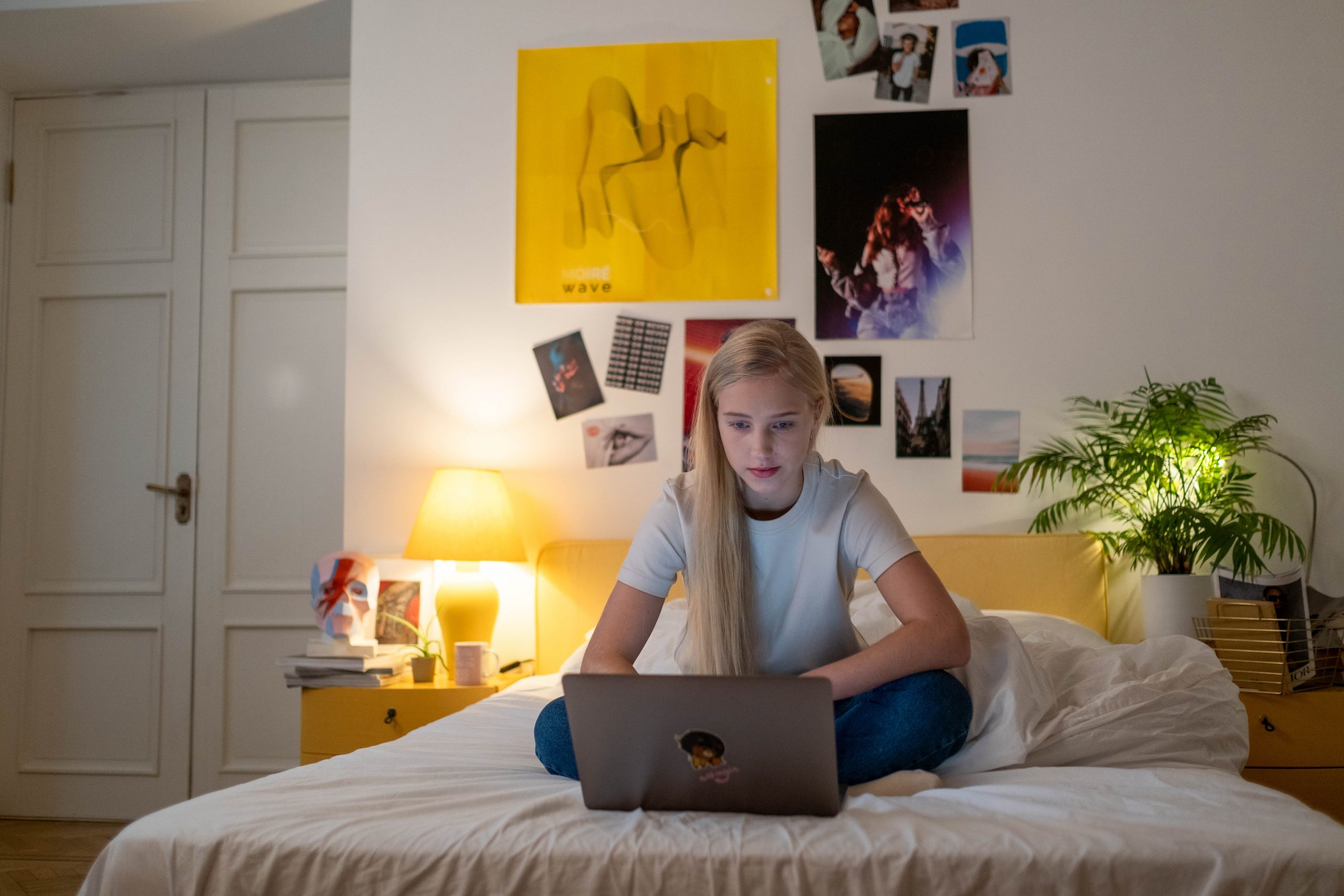 Young woman sitting on a bed working on a laptop