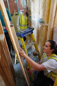 Woman working on construction site, smiling and measuring