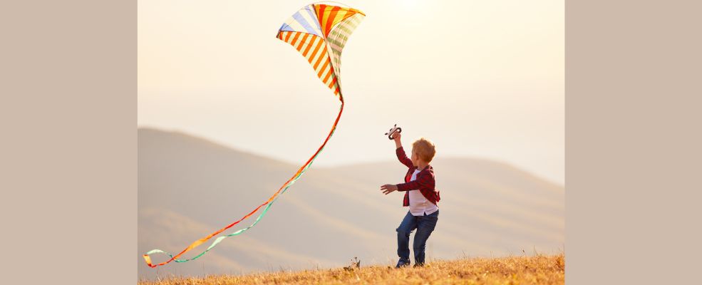 Happy child boy running with kite at sunset outdoors stock photo