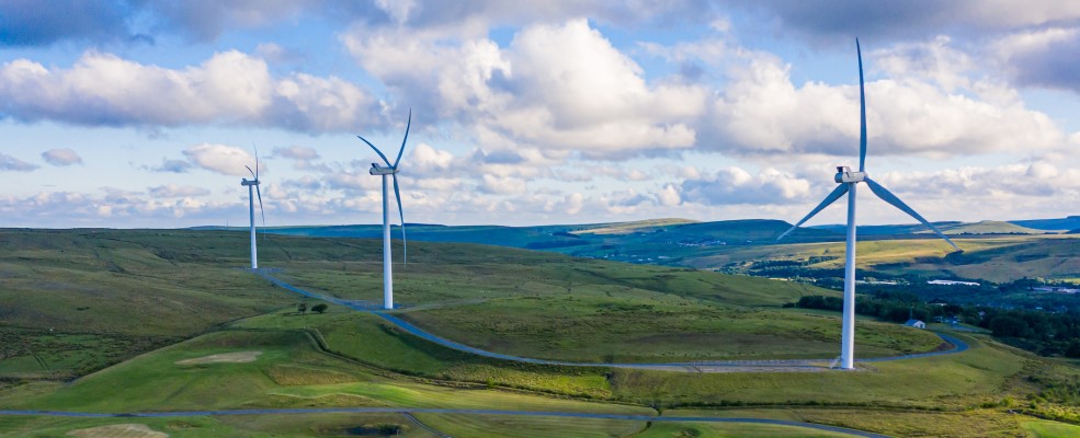 Aerial drone shot of several clean energy wind turbines in a rural area of South Wales.