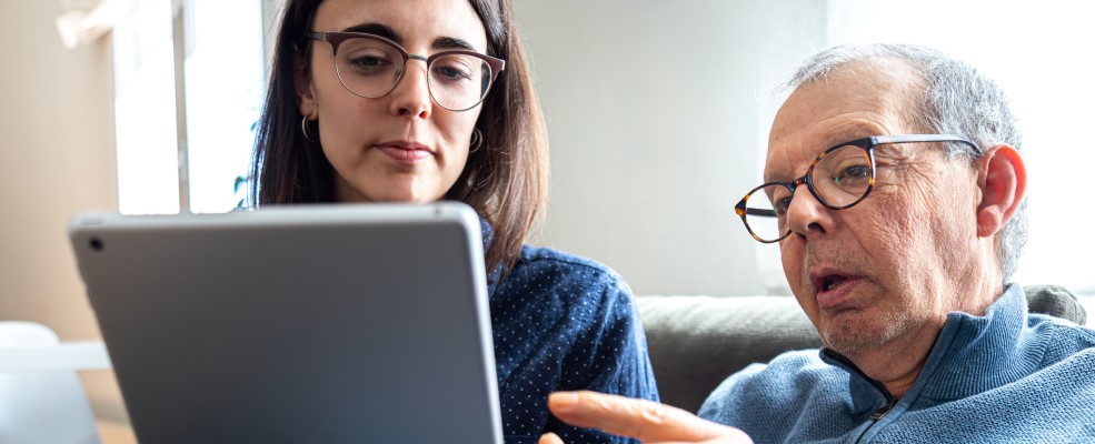 Senior man explaining to his young daughter with help of digital tablet.