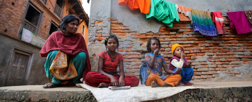 Woman with daughters and son in town, sitting on wall.